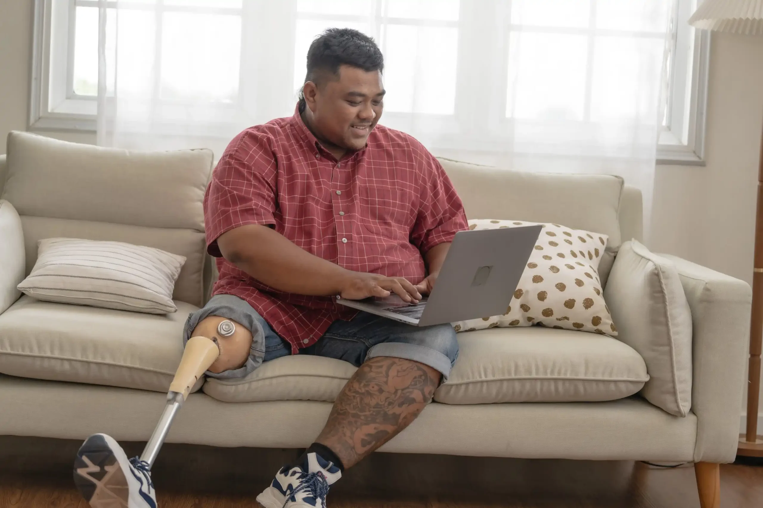 Disabled man sitting on couch using laptop