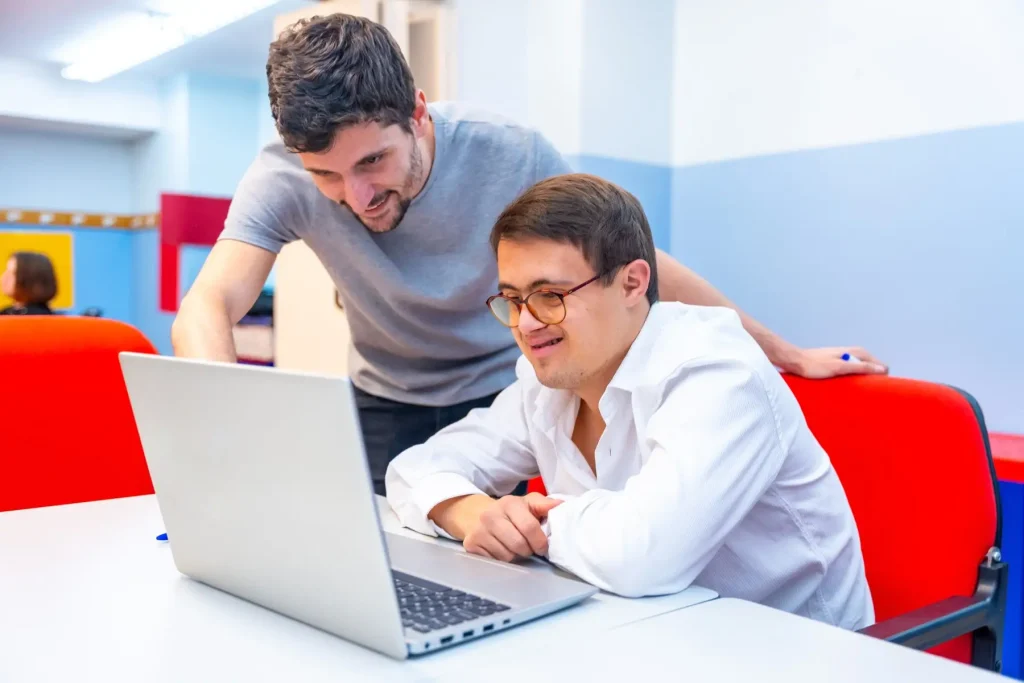 Disabled man with support worker looking at laptop