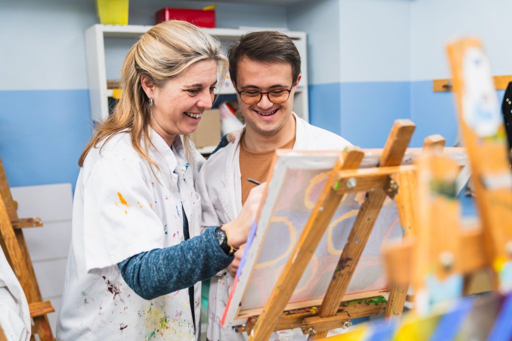 Disabled man in art class with support worker
