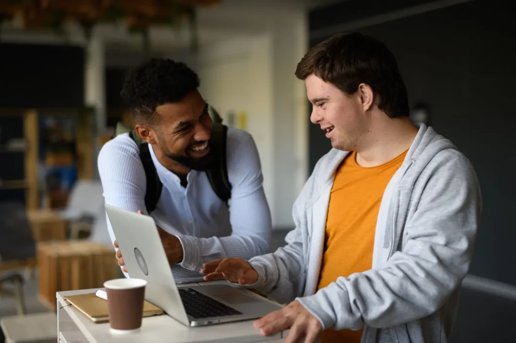 Disabled man using laptop with support worker