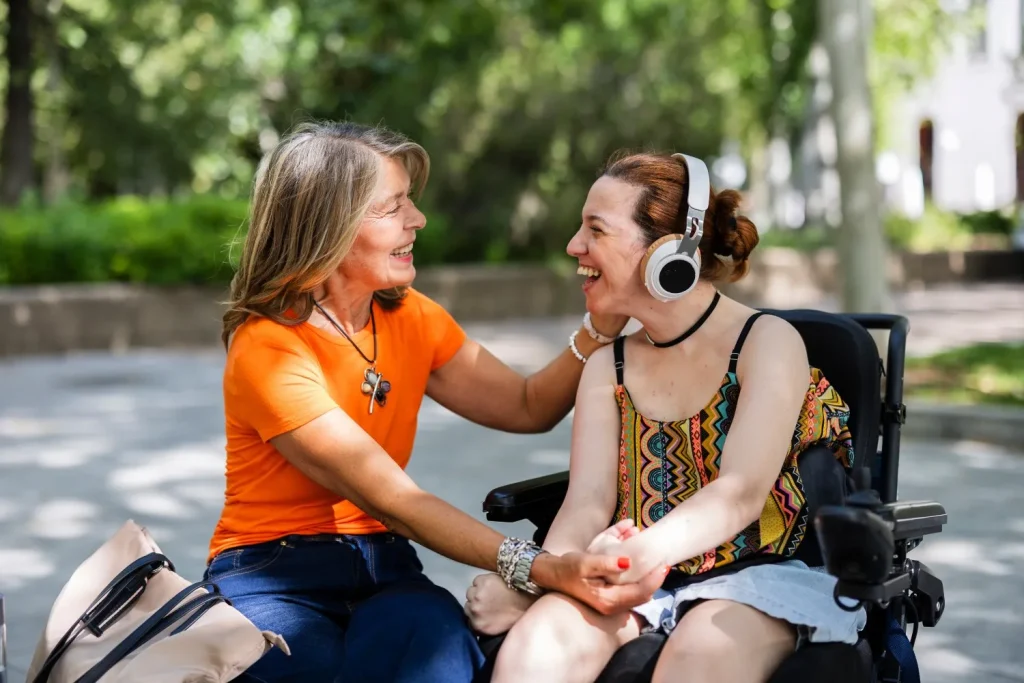 Disabled woman in wheelchair laughing with support worker