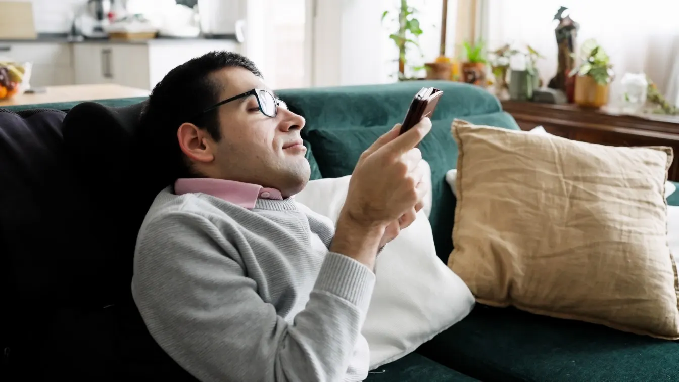 Disabled man on couch using mobile phone